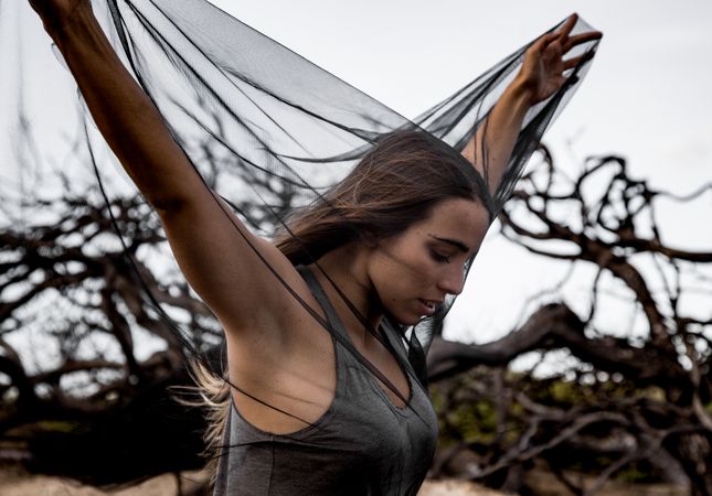 Woman posing on twigs of dry trees