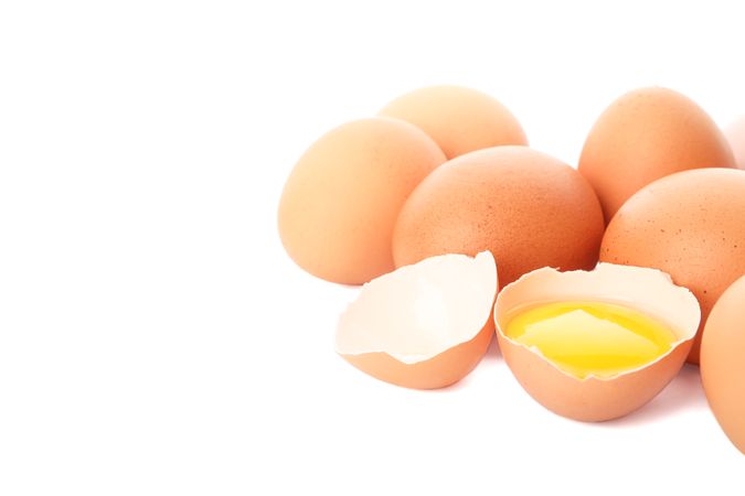 Chicken eggs and half yolk isolated on light background