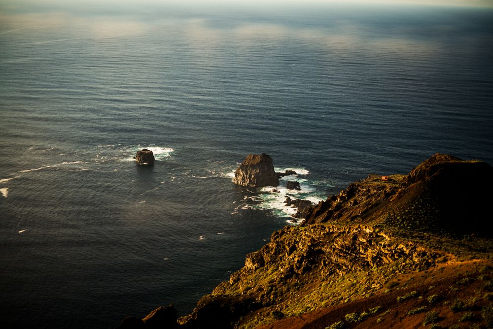 Looking down at boulders in ocean from cliff