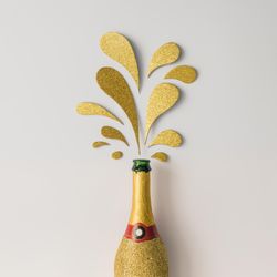 Champagne bottle with golden glittering splashes on light background