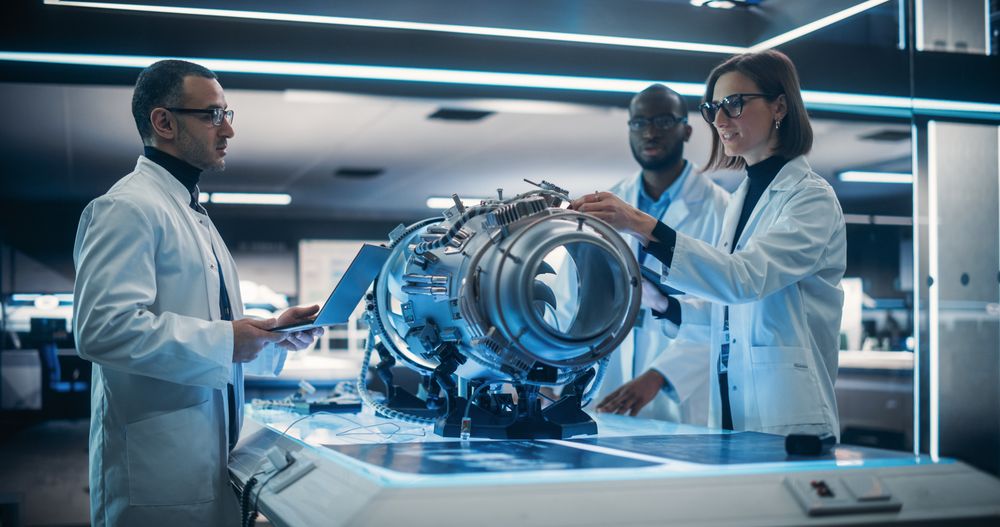 Diverse Multiethnic Team of Industrial Engineers Gathered Around a Table With an Innovative Turbine Engine.