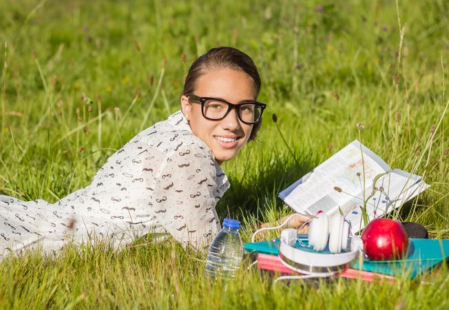 young student reading a book in the park