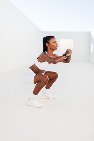 Slim woman practicing squats in outdoor studio