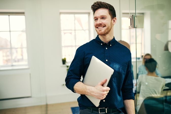 Portrait of smiling man holding laptop in the office