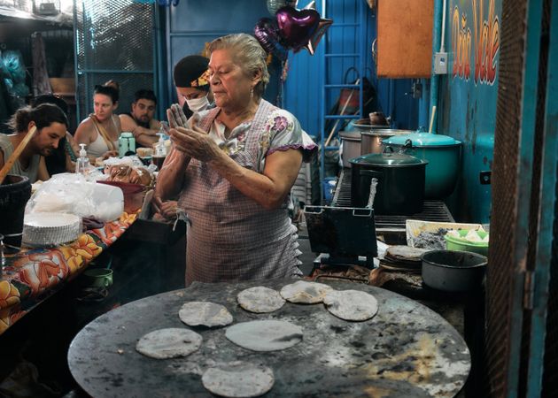 Woman preparing tortillas at outdoor food stall