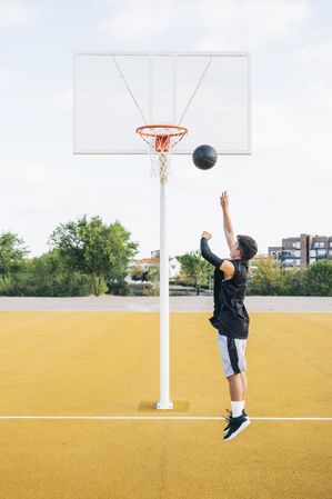 Young man playing on basketball court outdoor.