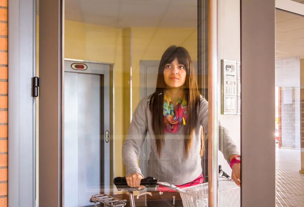 Female with fixie bike opening a glass door to exit