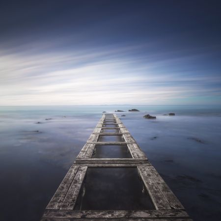 Wooden pier remains in a blue sea, long exposure
