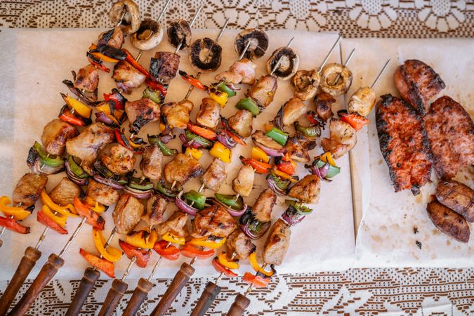 top view of plate with skewers sticks of pork with vegetables and chorizo