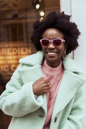 Smiling woman in turquoise jacket wearing sunglasses