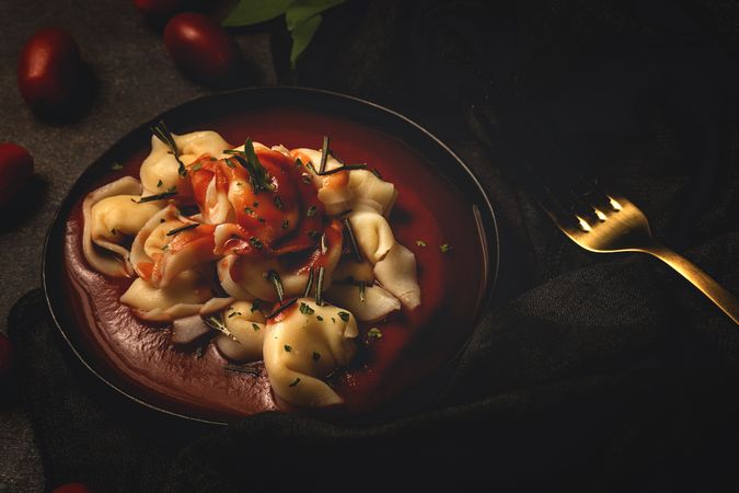 Plate of delicious ravioli with tomato sauce served on table