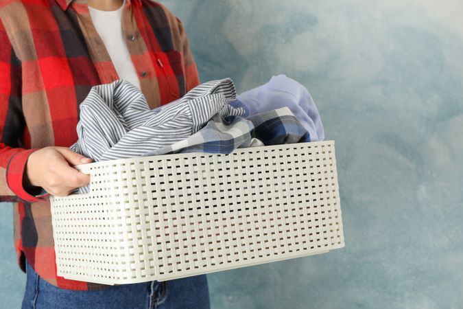 Young woman hold basket with clean clothes, space for text