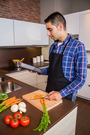 Man checking digital tablet for instructions as he prepares dinner