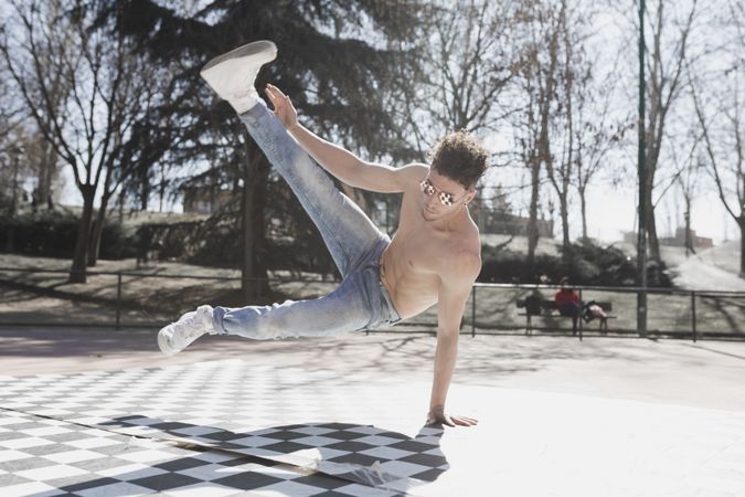 Shirtless man dancing break dance in park