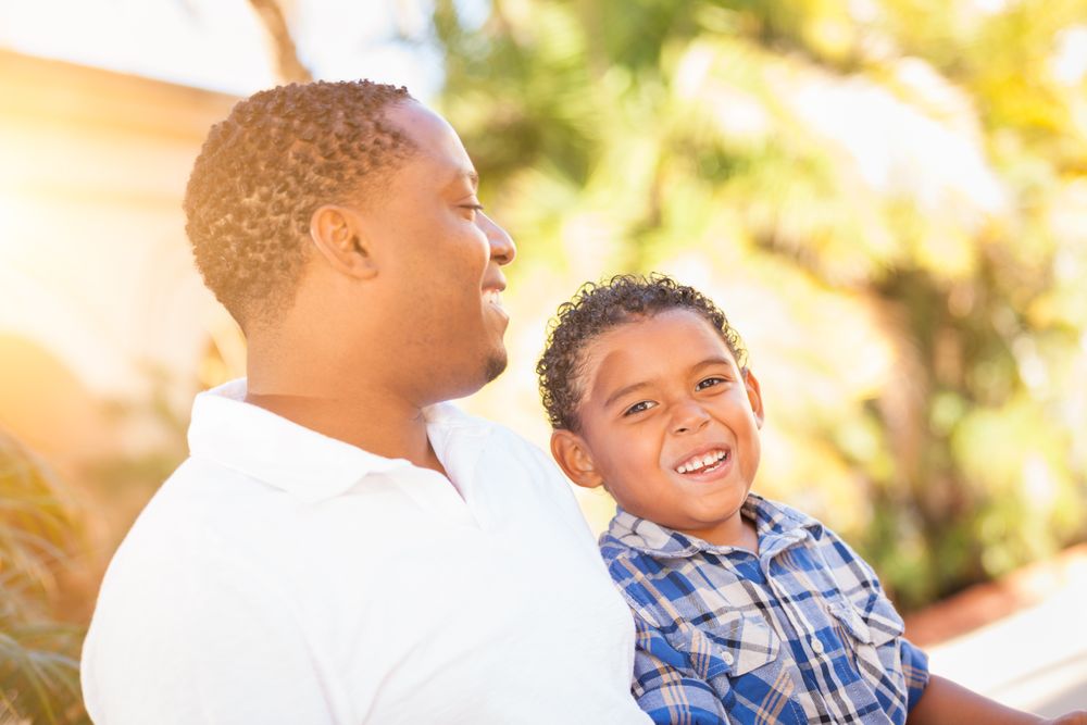 Black Son Laughing With Father Outdoors