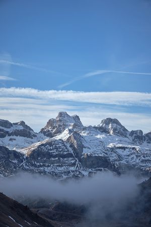 Snowy mountains and mist against blue sky