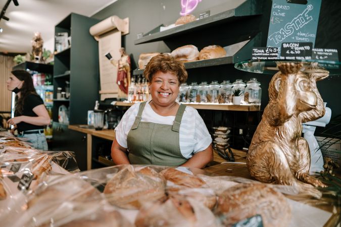 Portrait of older Black woman behind pastries at cafe counter