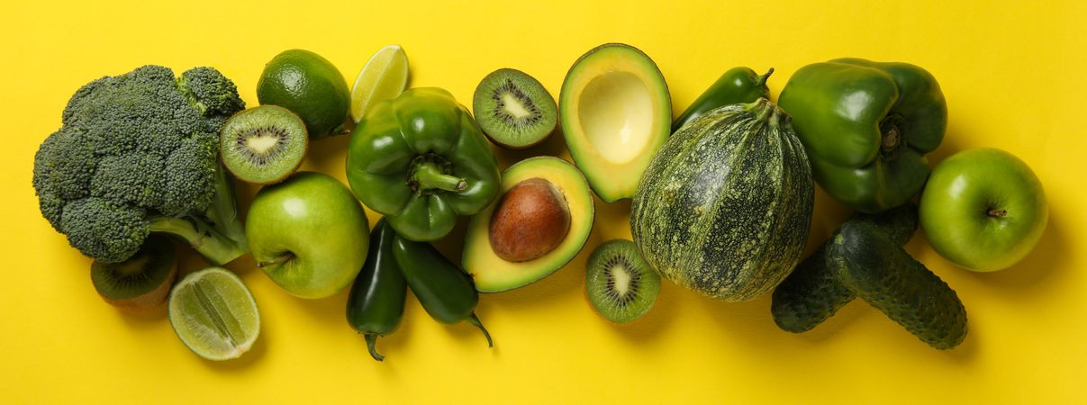 Green vegetables and fruits on yellow background