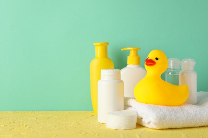 Baby hygiene accessories on yellow table against mint background