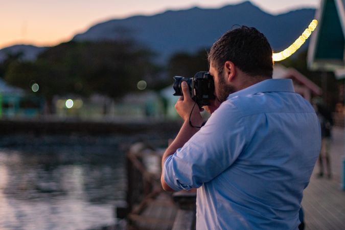 Man in blue dress shirt holding dark DSLR camera