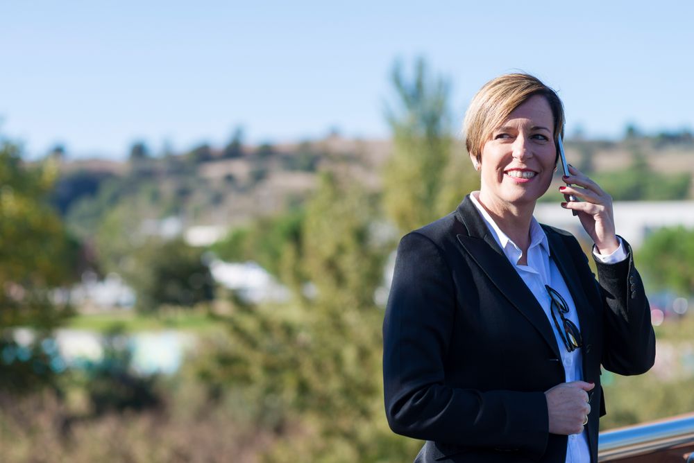 Happy woman standing on balcony speaking on phone