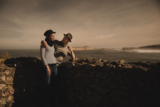 Man holding woman on hands near stones on shore
