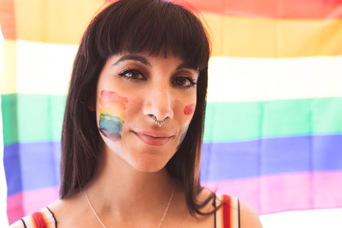 Happy brunette woman with LGBTQIA symbol on face