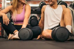 man and woman exercise workout in gym fitness breaking relax with dumbbell on the floor