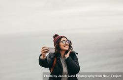 Smiling woman taking a selfie against ocean 4Bx1B0