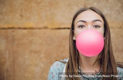 Young woman looking at camera with pink bubble gum 5lVEle