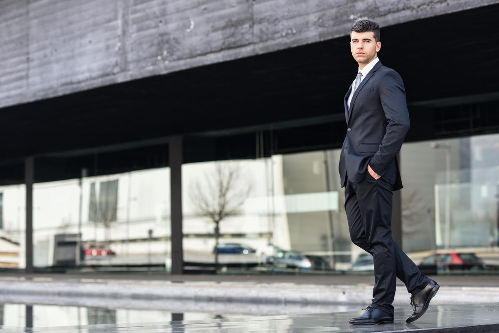 Man standing in suit and tie with hands in pockets