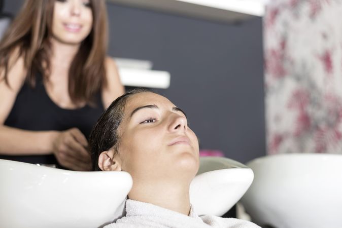 View of woman with head in sink at hairdressers