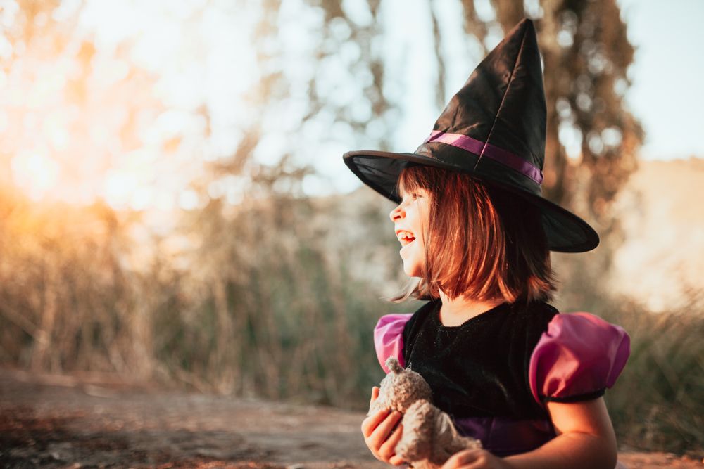 Joyful girl in witch costume at sunset