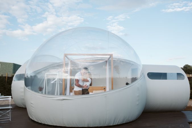 Affectionate couple looking at each other and kissing near bubble hotel