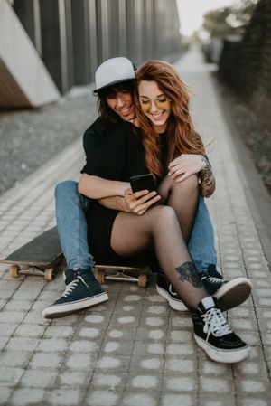 Skaters sitting on road on smartphone
