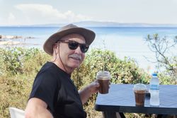 Cheerful man having drink on coastal terrace