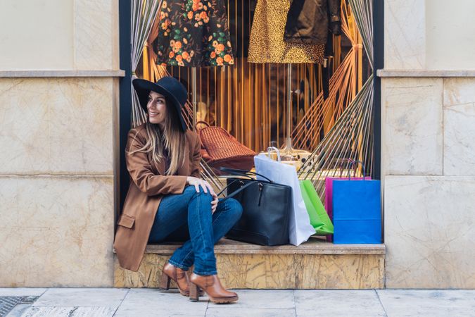 Content young woman in casual outfit resting on street after shopping
