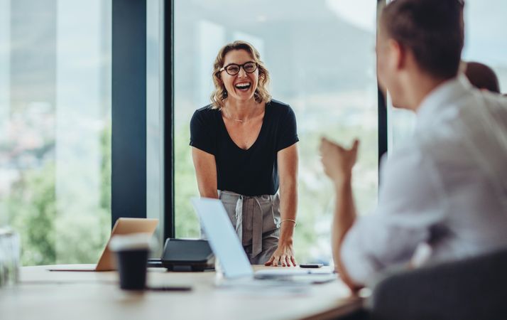 Female executive laughing while speaking to colleague during discussion