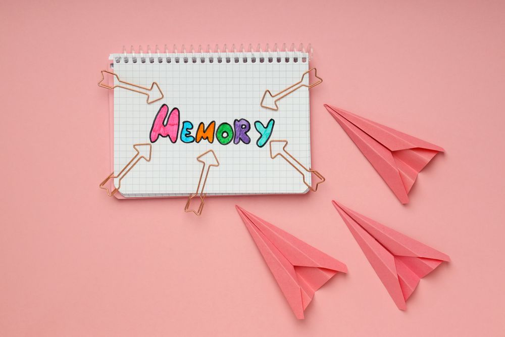Notepad with “memory” written in colorful markers with paper planes
