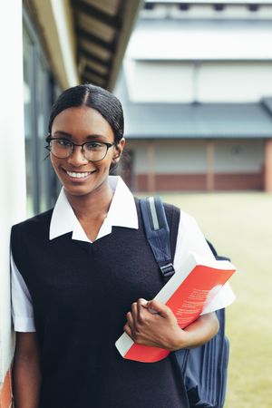 Smiling female student walking through school hallway looking at camera and smiling
