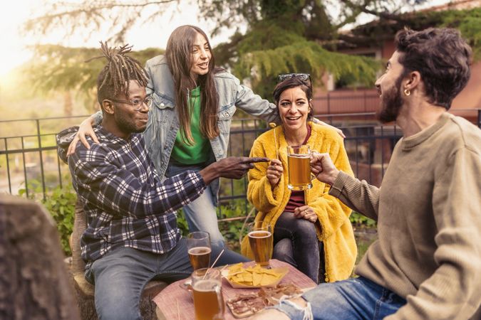 Multi-ethnic cheerful group of young people having a party together sitting & drinking