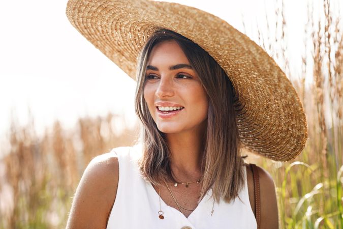 Portrait of smiling woman in field with straw hat