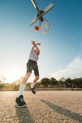 Boy throwing ball in hoop with hands raised