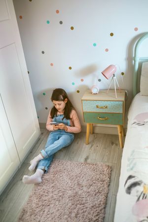Girl looking at the cell phone sitting on the floor