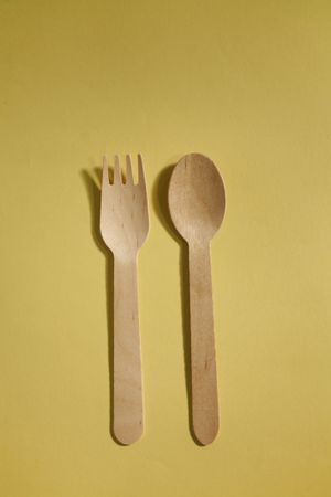 Disposable fork, spoon on yellow background