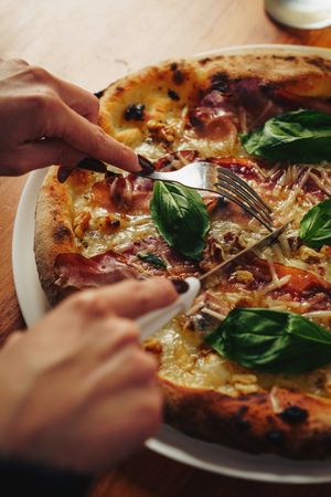 Gourmet pizza with pork, cheese, vegetables, herbs and drink on wooden table