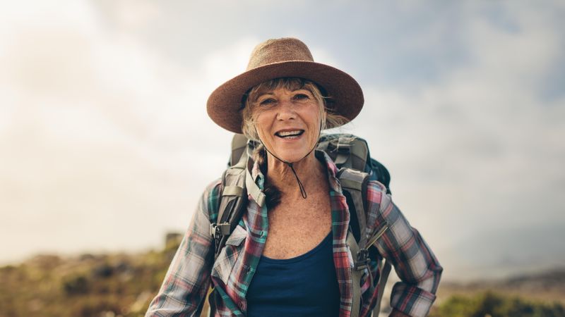 Cheerful woman enjoying her hiking trip standing outdoors
