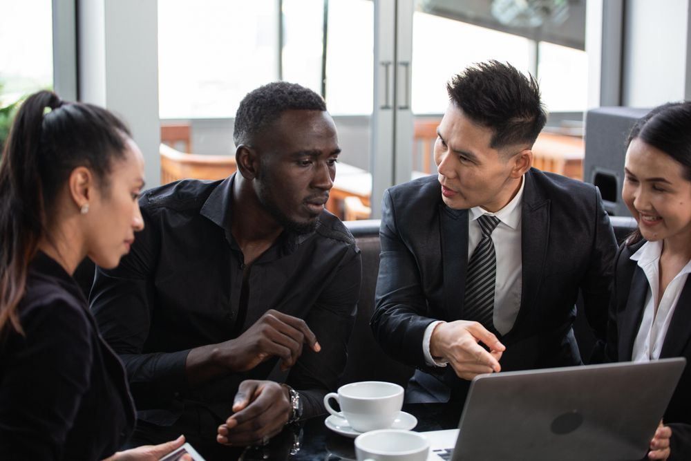 Diverse group of business people having a meeting in coffee shop over laptop