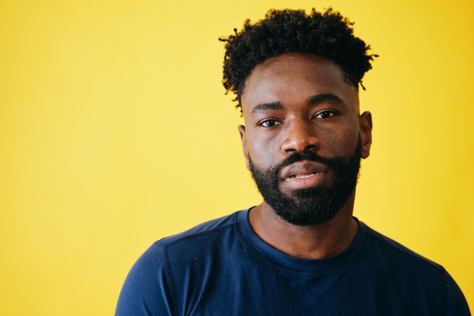 Close up portrait of relaxed Black man in navy t-shirt in light studio