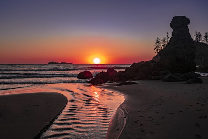 Sunset over Pacific Ocean seen from rocky beach